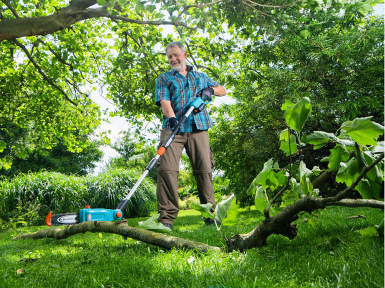 Un homme utilise une tronçonneuse Gardena pour couper une branche.