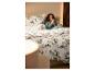 Femme au lit avec une parure de lit en flanelle fine LIVARNO® au motif de forêt d'hiver.