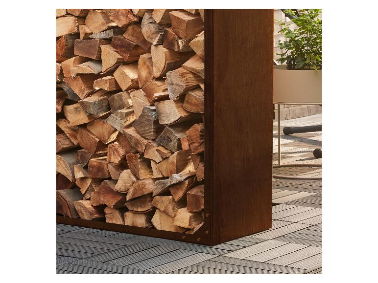 Pile de bois de chauffage dans un support métallique à côté d'une plante en pot sur un plancher en bois.