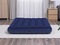 Un matelas pneumatique bleu foncé sur un tapis blanc dans une chambre.
