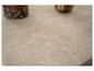 Surface en marbre beige avec un vase scintillant et un objet doré flous en arrière-plan.