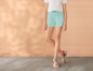 Un mannequin porte un short bleu clair et des sandales colorées.