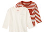Deux t-shirts à manches longues pour bébé, un rayé et un uni, de la marque Lupilu.
