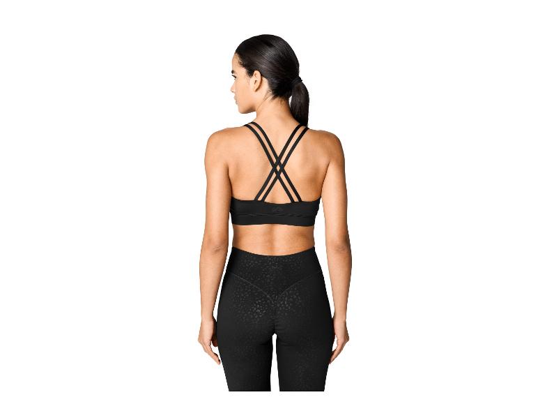 Vue arrière d'une femme en brassière de sport noire à bretelles croisées et leggings noirs à motifs.