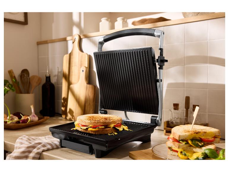 Un grill ouvert avec un sandwich grillé et un autre sandwich dans une assiette.