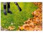 Homme utilisant un souffleur de feuilles électrique pour nettoyer les feuilles d'automne d'une pelouse.