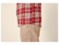 Chemise à carreaux rouges et beiges avec un pantalon beige.