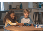 Deux enfants assemblent un puzzle 3D de voiture bleue sur une table en bois.