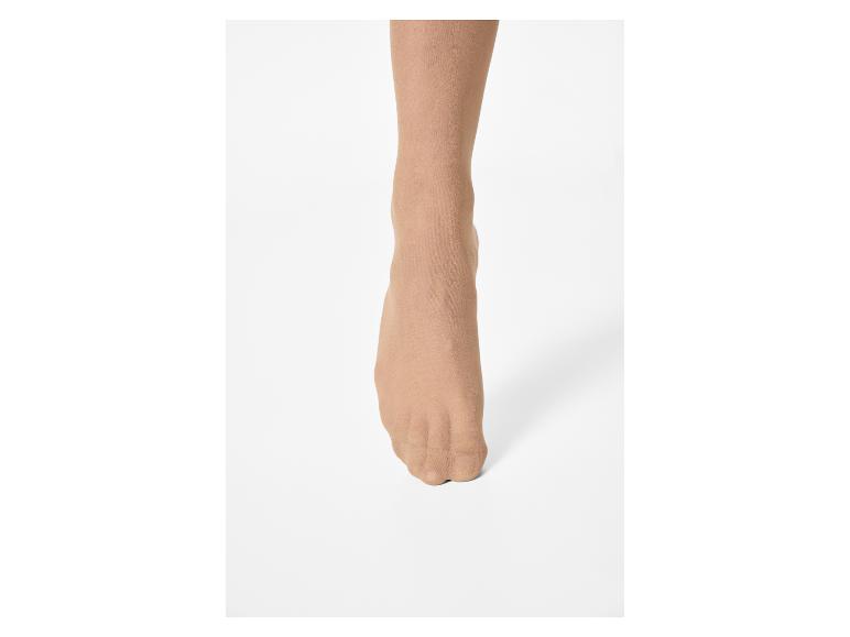 Jambe et pied de femme avec des collants couleur chair sur fond blanc.