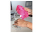 Un chiffon en microfibre rose est utilisé pour sécher un verre à vin en verre.