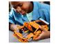 Un enfant joue joyeusement avec une voiture jouet orange au capot ouvert.