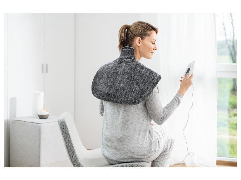 Femme portant un coussin chauffant électrique sur les épaules, tenant une télécommande.