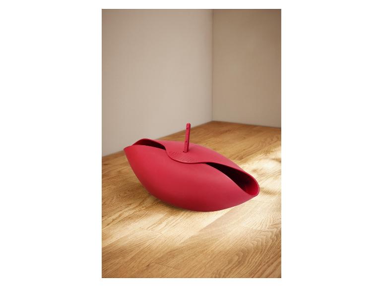 Un panier à pain rouge en forme de pétale sur une surface en bois.