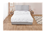 Une couette blanche matelassée sur un lit gris dans une chambre moderne.