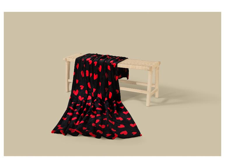 Couverture noire à cœurs rouges sur un banc en bois clair