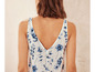 Une femme porte un top blanc en lin avec un motif floral bleu.