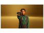 Homme tenant une visseuse sans fil, portant une veste de sport verte et noire.