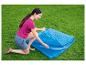 Une femme prépare une couverture de piscine bleue pour l'été.