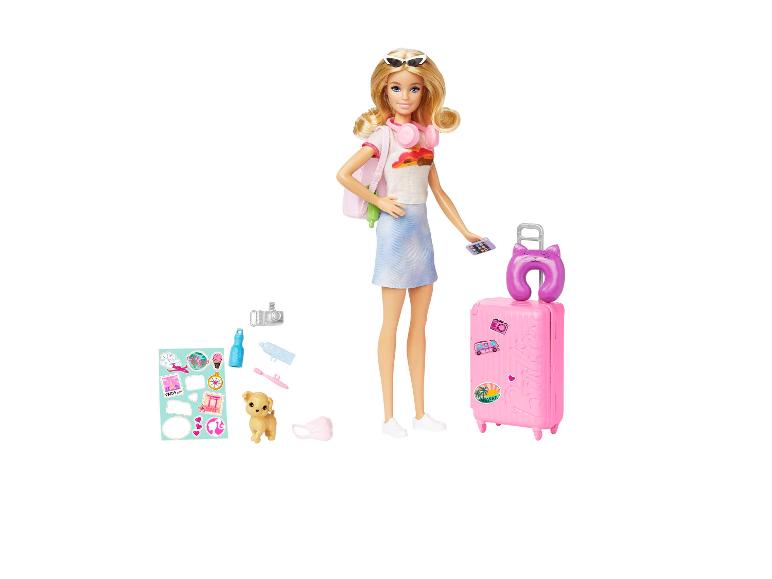 Poupée avec valise de voyage, sac à dos, chien et accessoires sur fond blanc.