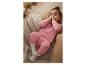 Bébé en grenouillère rose allongé sur une couverture tricotée, avec des jouets en bois en arrière-plan.