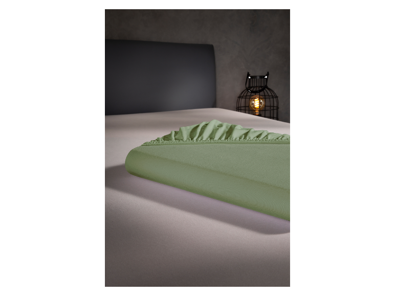 Protège-matelas vert olive sur un lit.