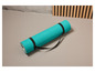 Un tapis de yoga turquoise avec une sangle noire