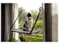 Chat noir et blanc assis sur une étagère de fenêtre, avec des arbres verts en arrière-plan.