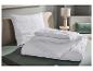 Oreiller et couette blancs dans une chambre avec un lit vert et un canapé beige.
