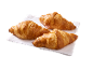 Trois croissants dorés sur une serviette blanche, prêts à être dégustés.