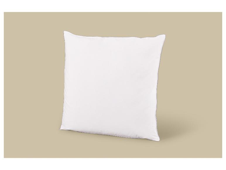 Un oreiller blanc avec une bordure grise, debout sur un fond beige.