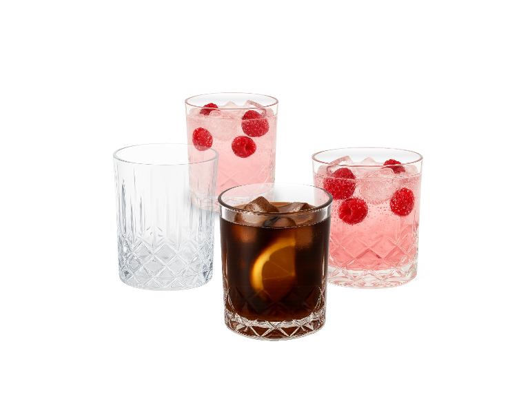 Quatre verres, deux avec boisson rose et framboises, un avec cola et citron, et un vide.
