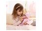 Fille en haut rose jouant avec une poupée bébé en tenue rose et sucette.
