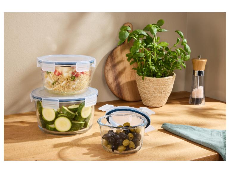 Récipients alimentaires en verre avec ingrédients frais sur un comptoir en bois.