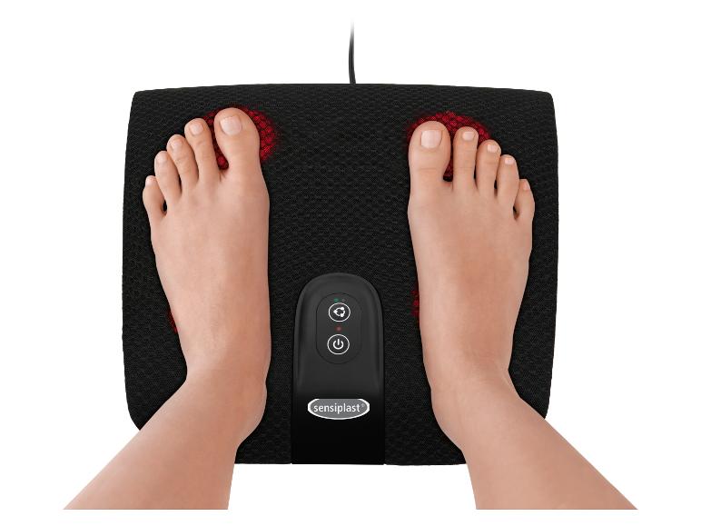 Pieds sur un masseur de pieds électrique noir avec lumières rouges et panneau de commande.