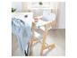 Chaise haute blanche et en bois avec bol et cuillère, à côté d'une table avec un tissu bleu.