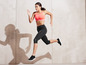 Une femme en soutien-gorge de sport rose et leggings noirs courant devant un fond clair.
