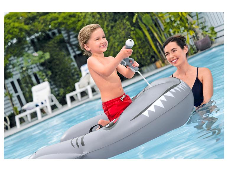 Garçon sur matelas requin avec pistolet à eau dans la piscine avec une femme.