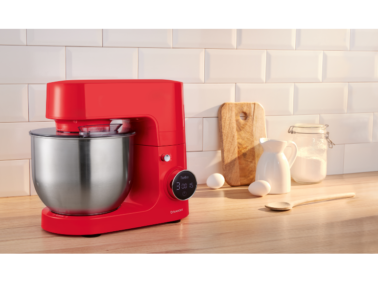 Robot pâtissier rouge sur un comptoir de cuisine avec des ingrédients de cuisson.