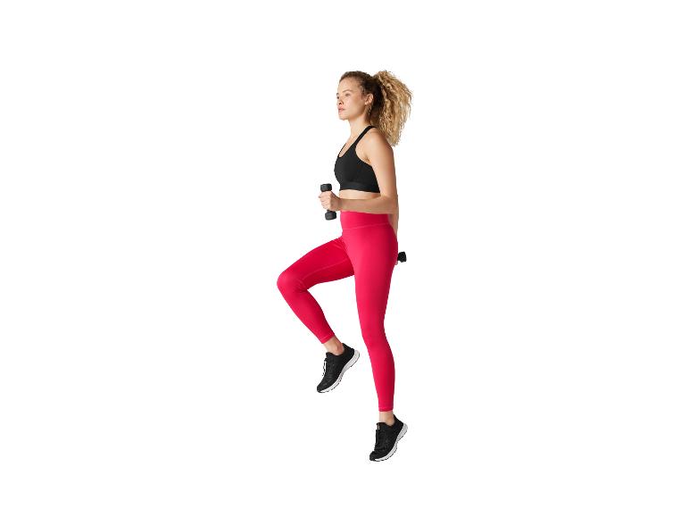 Femme en legging rose et brassière de sport noire faisant de l'exercice avec des haltères
