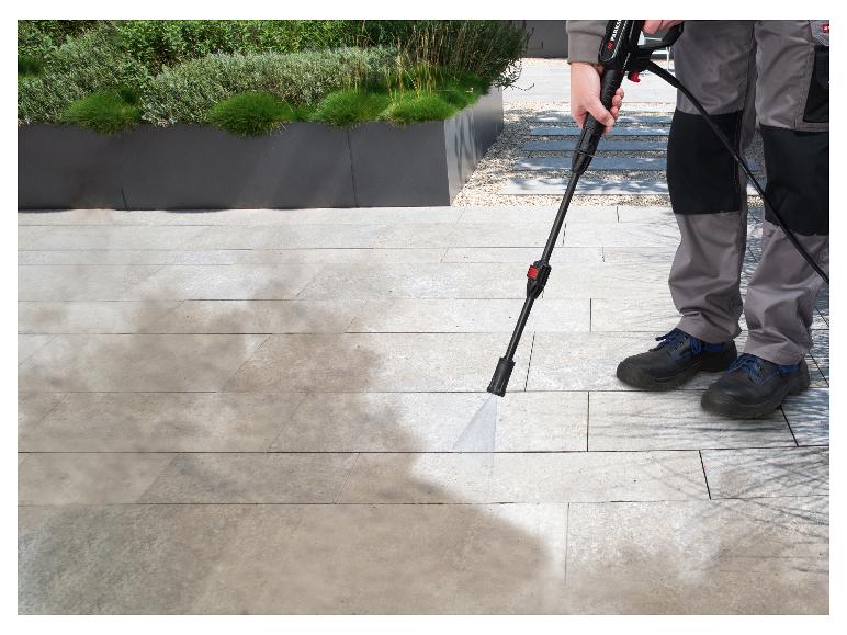 Une personne nettoie un pavé avec un nettoyeur haute pression Parkside.