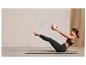 Une femme fait des exercices abdominaux avec un ballon de fitness rose Crivit sur un tapis de yoga.