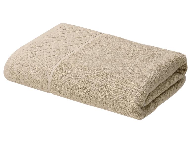 Serviette pliée beige avec une bordure à motifs