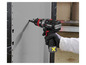 Une main tenant une perceuse-visseuse sans fil Parkside en train de percer un trou dans un mur gris.