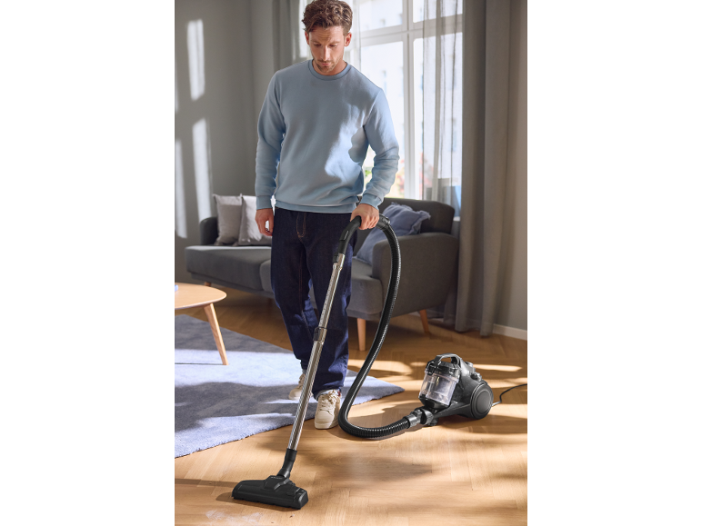 Homme passant l'aspirateur sur un parquet dans un salon.