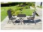 Table de jardin gris foncé et deux chaises sur une terrasse en bois avec un jardin vert en arrière-plan.