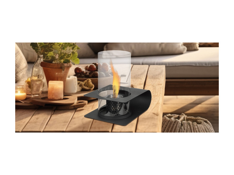Une table noire avec un photophore en verre avec une flamme à l'intérieur.