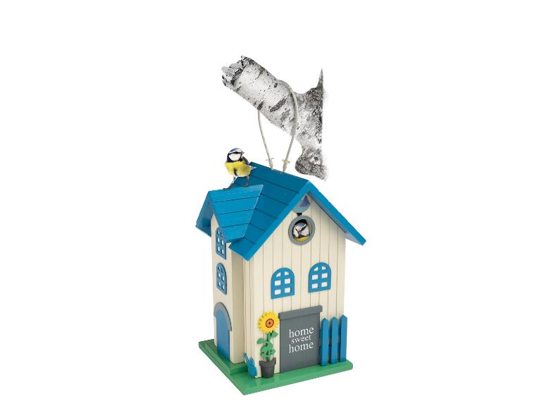 Nichoir avec un toit bleu, un tournesol et deux oiseaux, un sur le toit et un à l'intérieur.