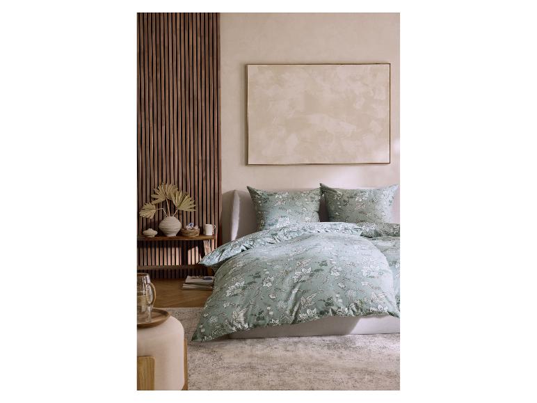 Chambre avec parure de lit florale vert menthe, lambris en bois et tableau.