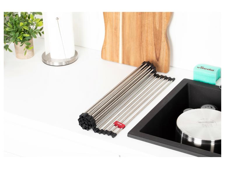 Égouttoir à vaisselle enroulable sur un évier de cuisine avec une planche à découper.