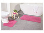 Deux tapis de bain roses dans une salle de bain avec une baignoire et des toilettes.